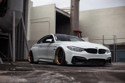 Sleek white BMW 4 Series with distinctive gold alloy wheels, showcasing a sporty and aggressive stance.