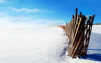 Paisaje cubierto de nieve con cerca de madera bajo un cielo azul claro