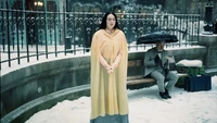 Emma Stone in a Yellow Cape Amidst a Snowy Urban Landscape