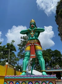 Estátua verde vibrante de Hanuman em uma atração turística em meio a uma vegetação exuberante e céus azuis