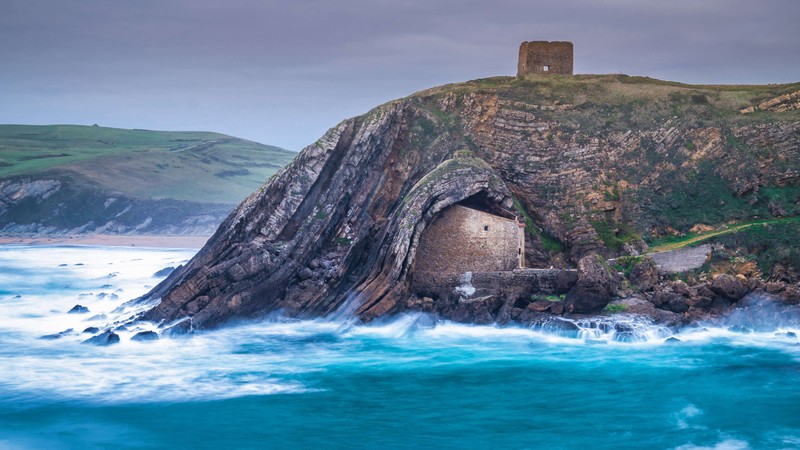 Um pequeno prédio em um penhasco acima do oceano (torre san telmo, marco histórico, espanha, penhasco, costeiro)