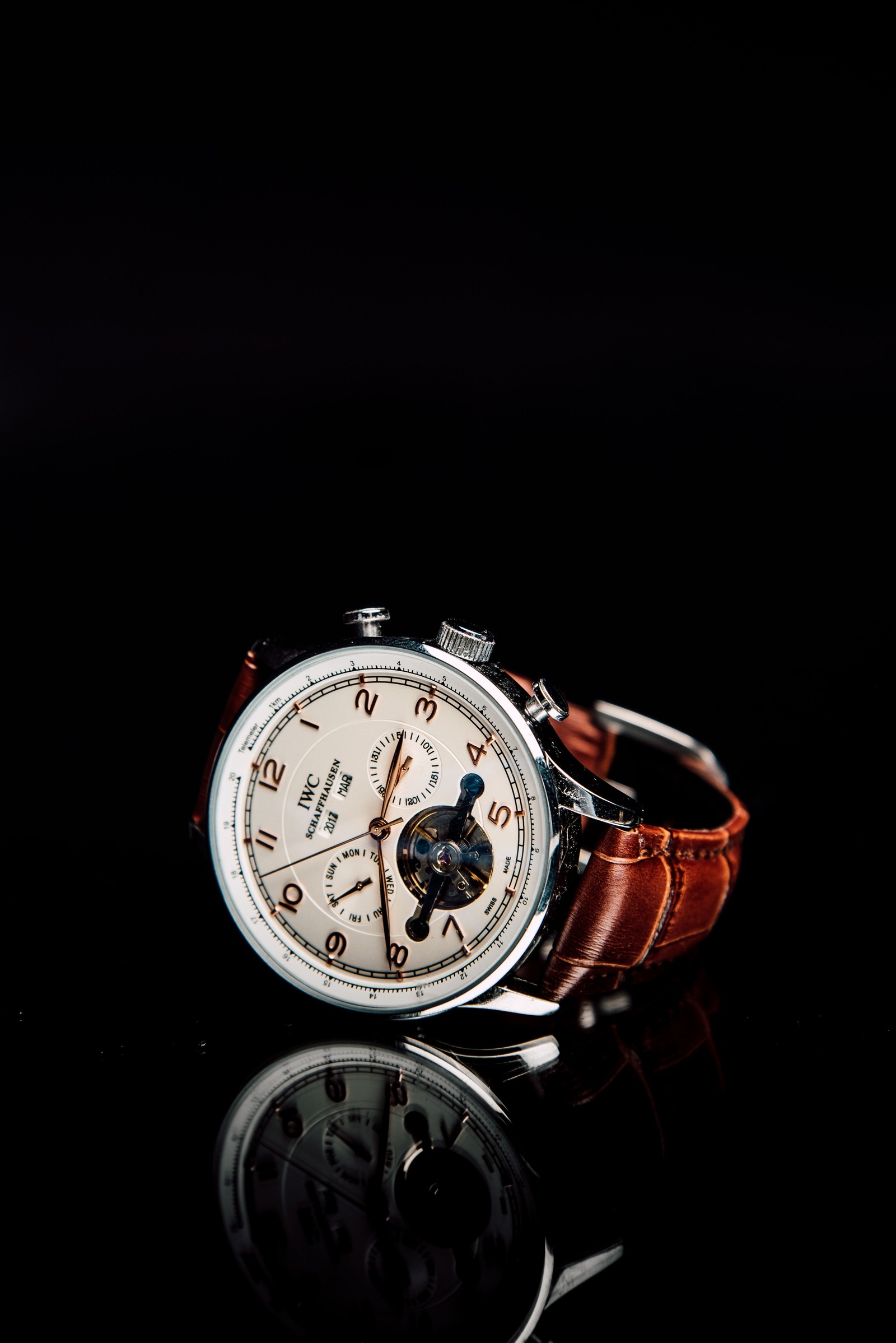 A close up of a watch with a brown strap on a black surface (watch, analog watch, watch accessory, fashion accessory, jewellery)