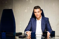 Cristiano Ronaldo en un traje formal, sentado en un escritorio con productos de fragancia de lujo.