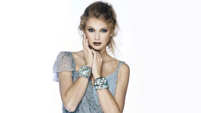 Taylor Swift en un elegante atuendo azul con maquillaje audaz contra un fondo blanco.