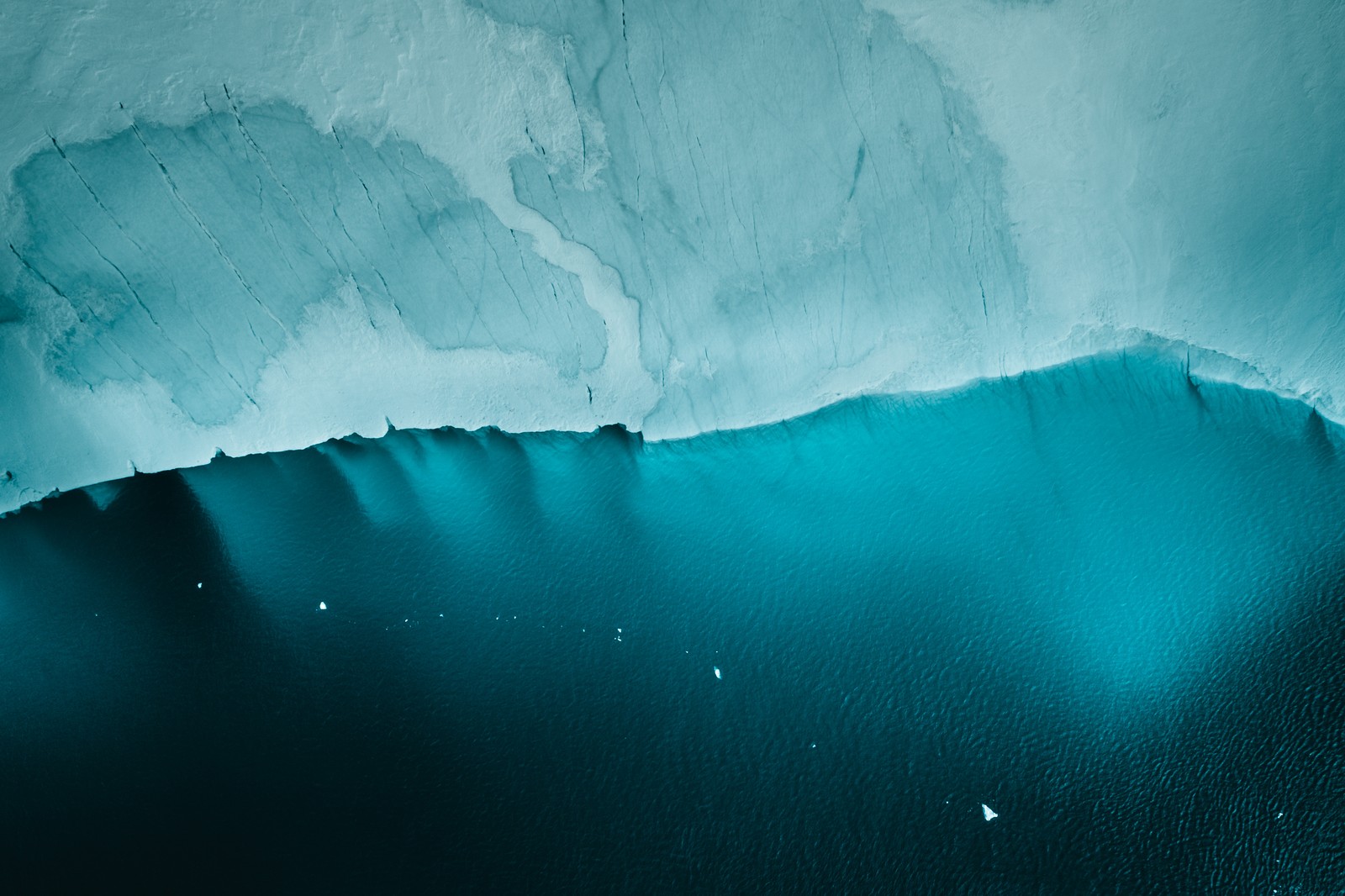 Un iceberg congelado con un pequeño bote en medio (islandia, glaciar, vista aérea, frío, acantilado)