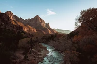 Paisaje de cañón sereno con majestuosas montañas y un curso de agua reflectante en el Parque Nacional Zion