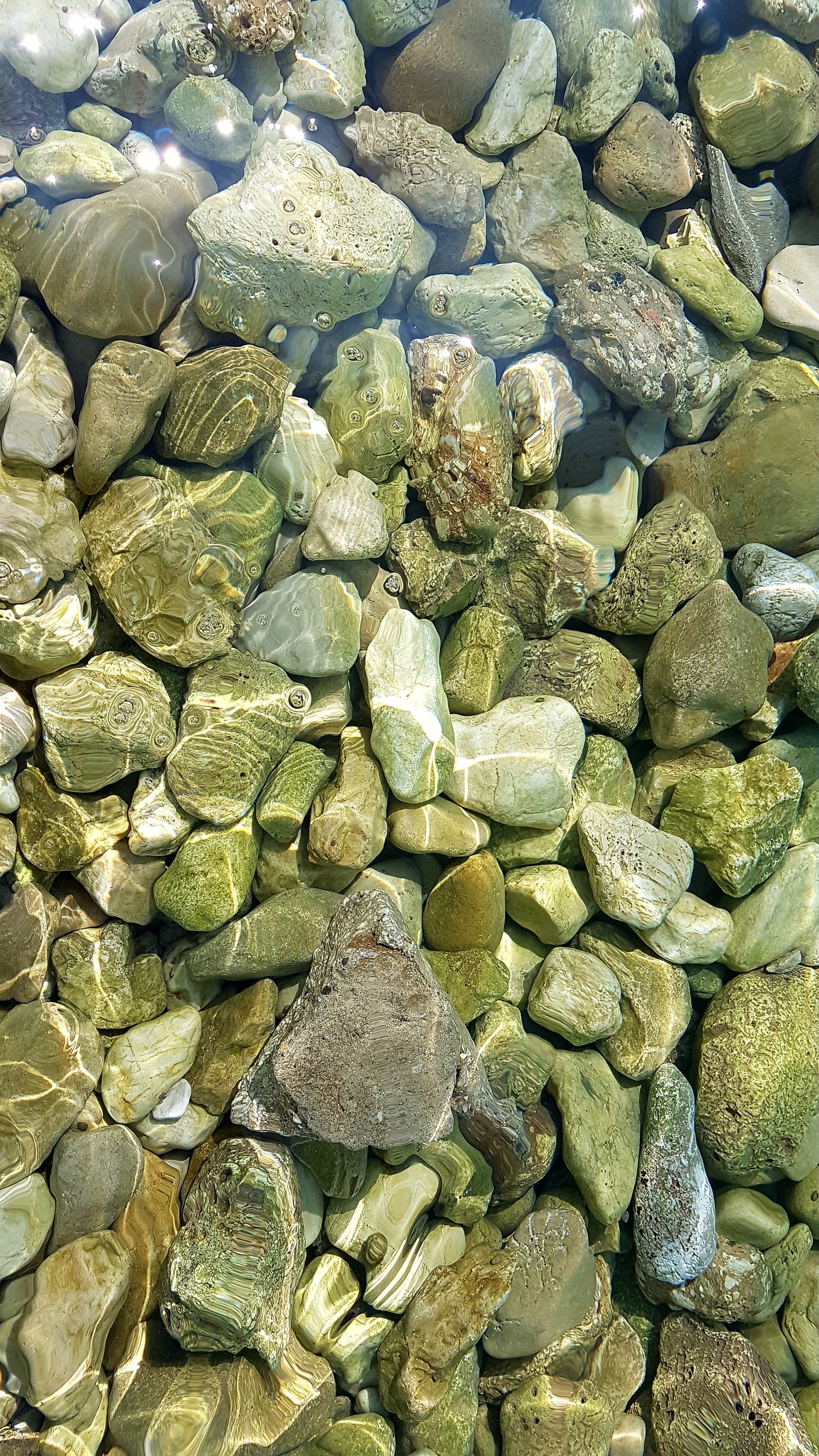 There is a lot of rocks and water in the water (clear water, rock, rocks, sea, stone)