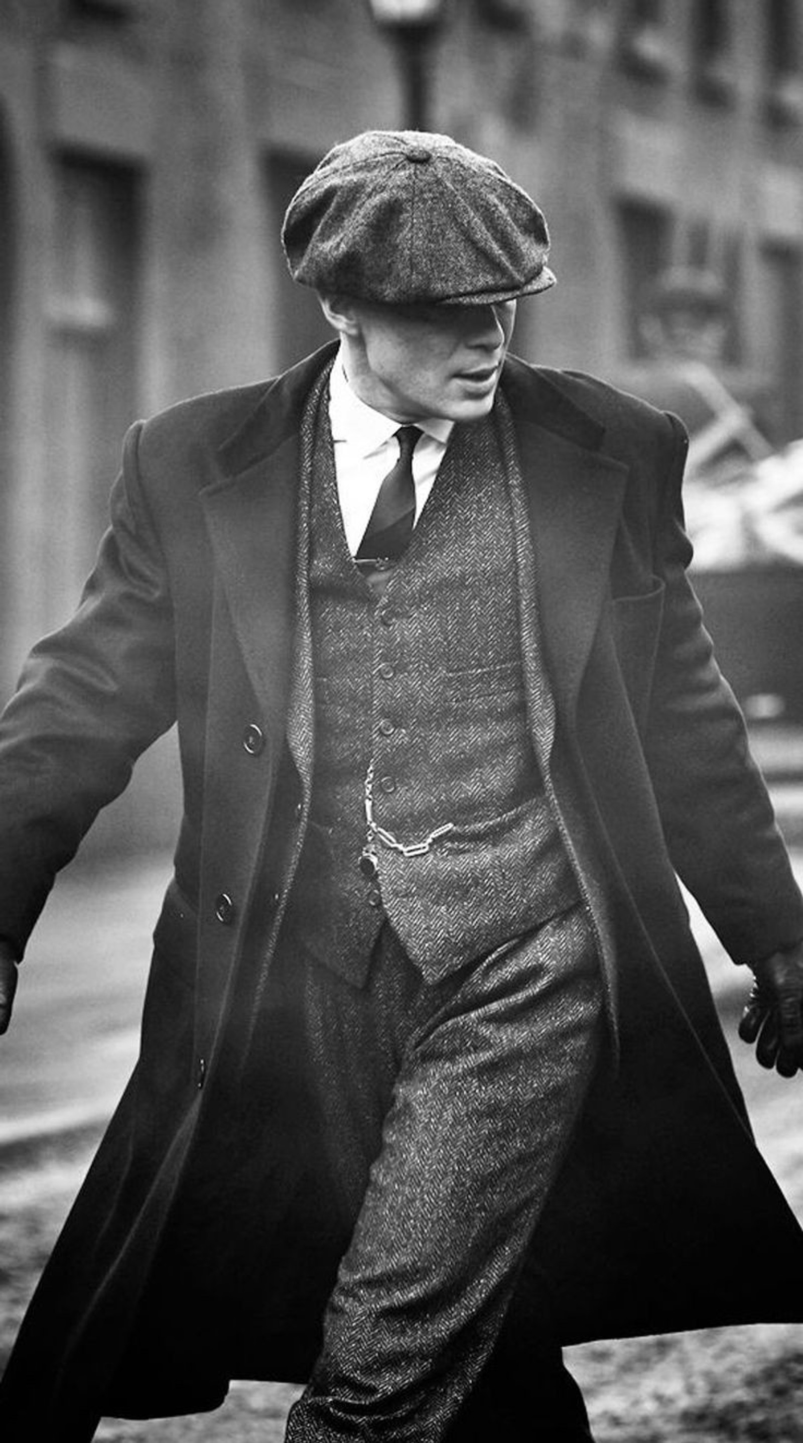 Un hombre con traje y sombrero caminando por una calle (netflix, peaky blinders, serie)