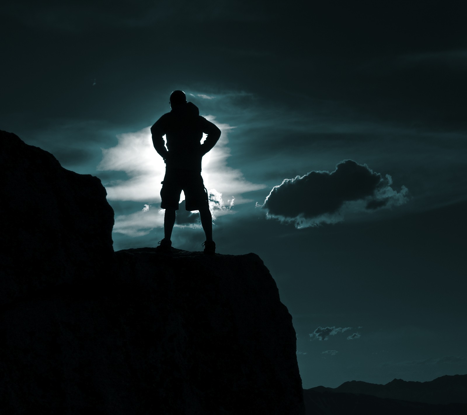 Image retouchée d'un homme debout sur un rocher, les bras croisés (nuages, lune, montagne, silhouette)