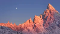 Chaîne de montagnes majestueuse sous un croissant de lune en plein jour