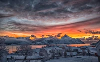 Atardecer de invierno sobre un fiordo cubierto de nieve y un pueblo de montaña