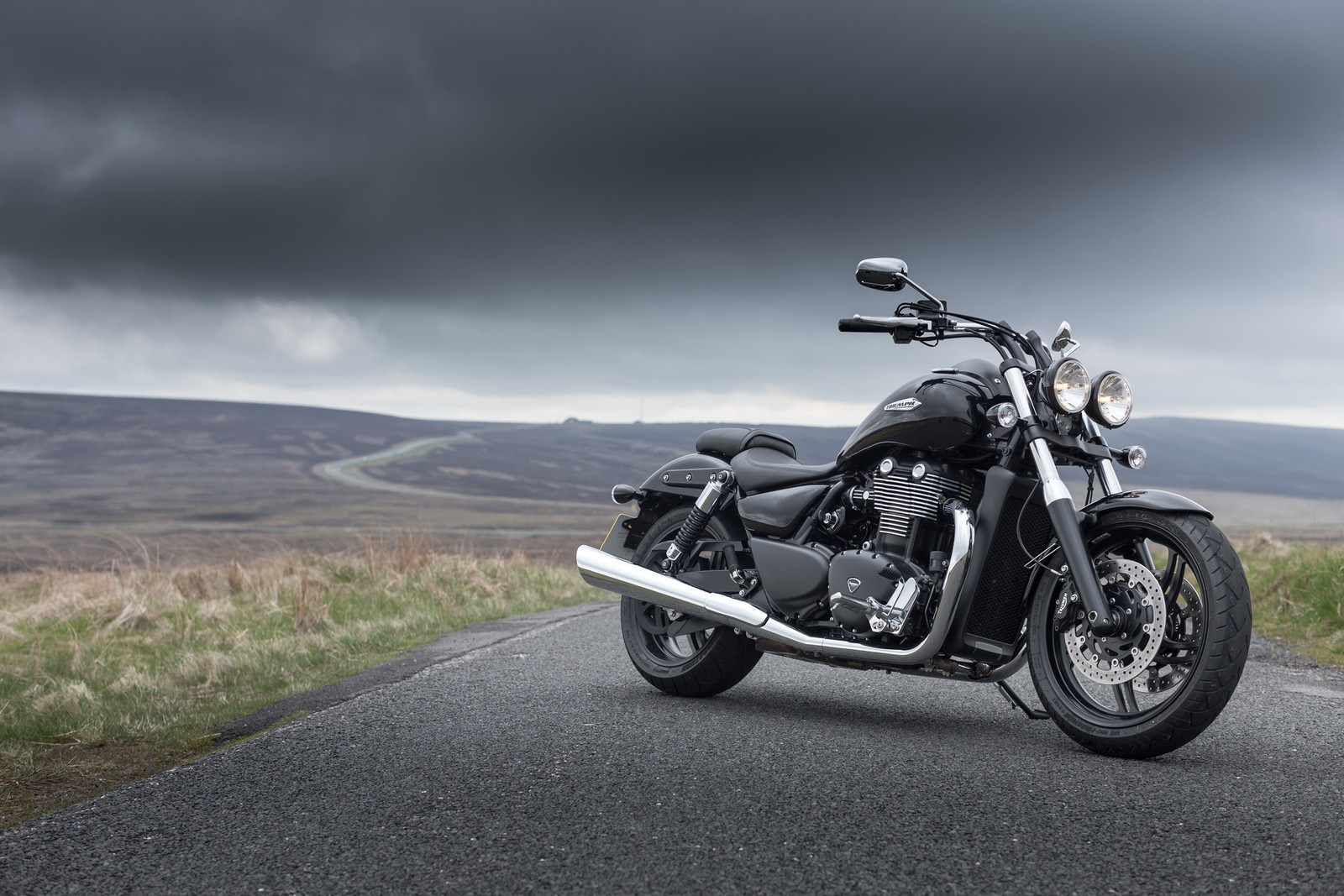 Una motocicleta estacionada en una carretera con un cielo nublado (triumph motorcycles ltd, motocicleta, crucero, coche, motociclismo)