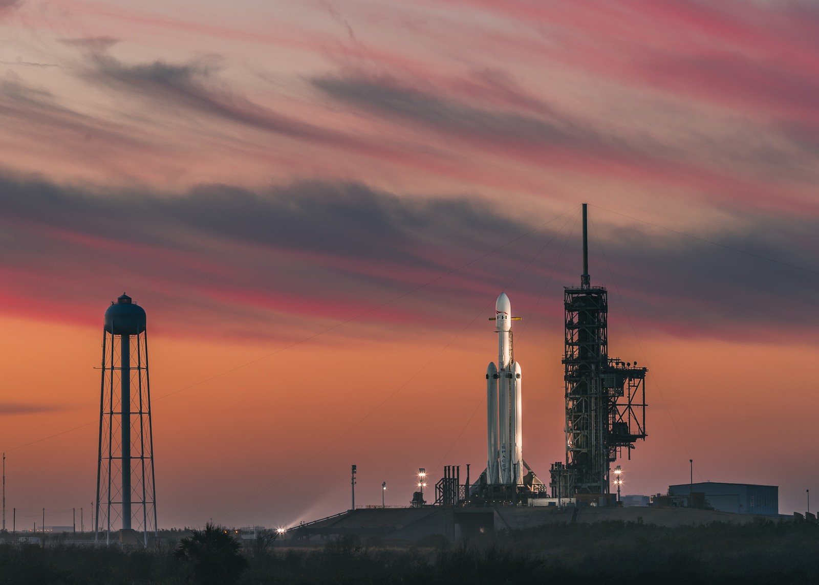 Vista aérea de una estación espacial con un cohete en la parte superior (spacex, falcon heavy, industria, resplandor, fábrica)