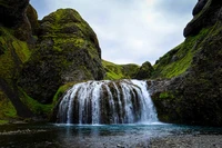 Cascada serena que fluye a través de acantilados verdes exuberantes