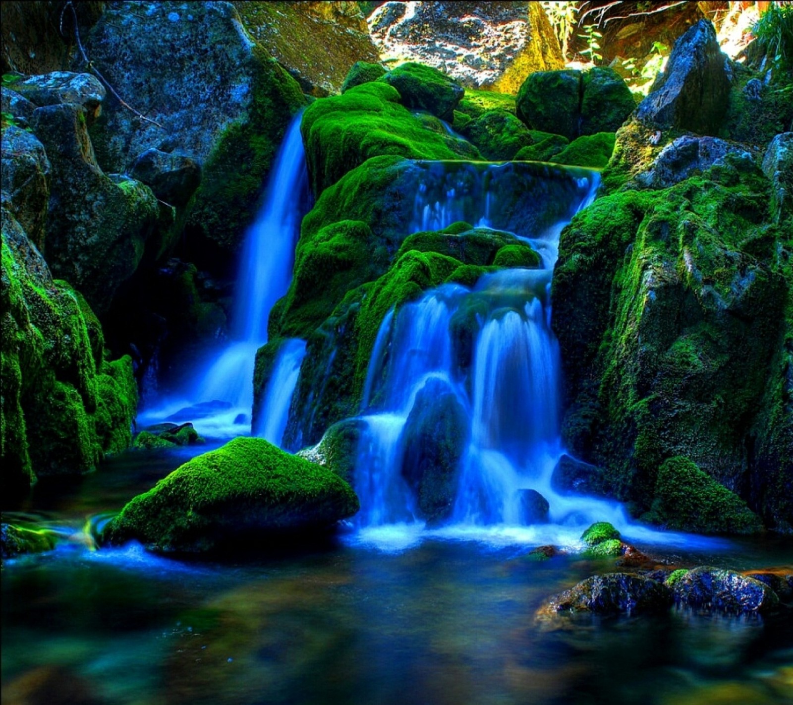 Un primer plano de una cascada con musgo creciendo en las rocas (bosque, lago, paisaje, naturaleza, rio)