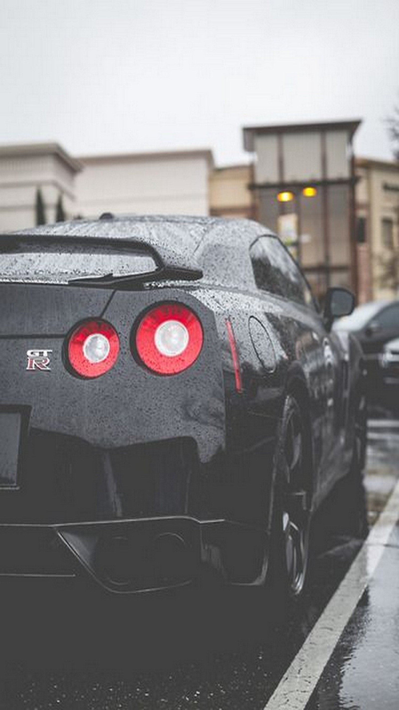 Un gros plan d'une voiture de sport noire garée sur une rue mouillée (gt r, gtr)