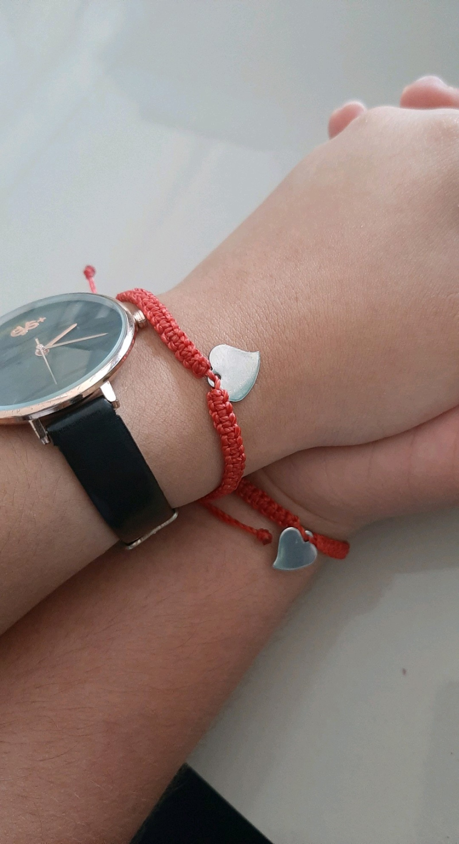 Quelqu'un tient un poignet avec une montre et un fil rouge (pour toujours, amour)