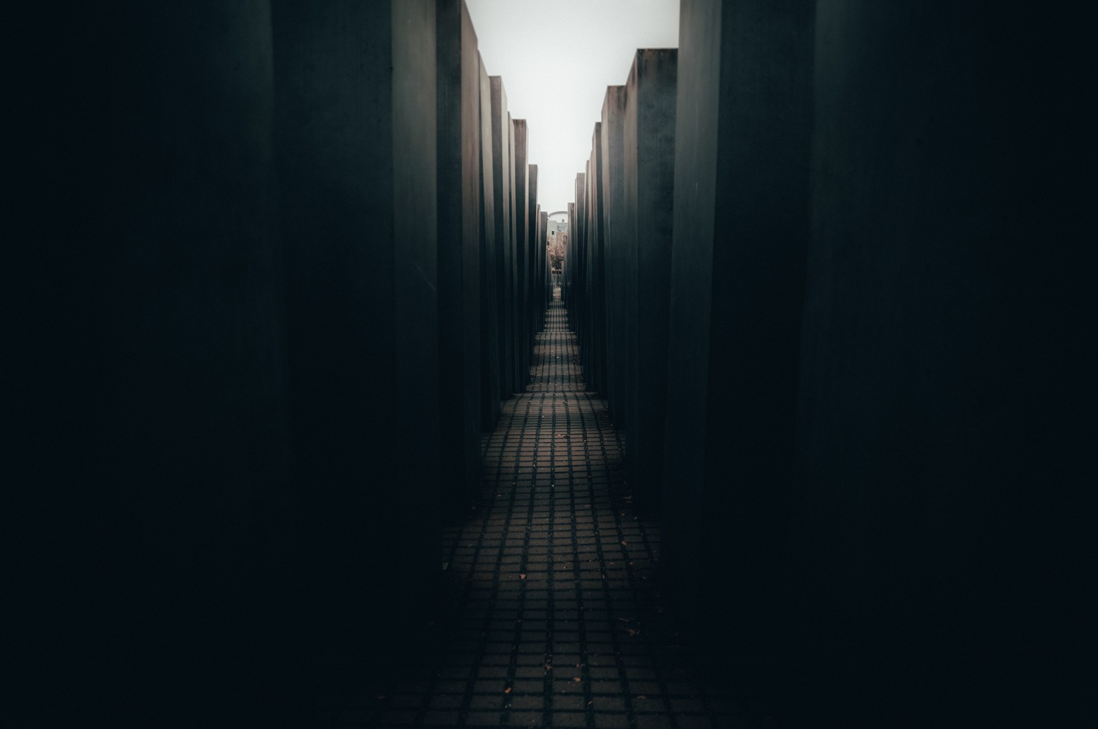 A view of a long hallway with a brick floor and a sky background (berlin, night, blue, darkness, architecture)