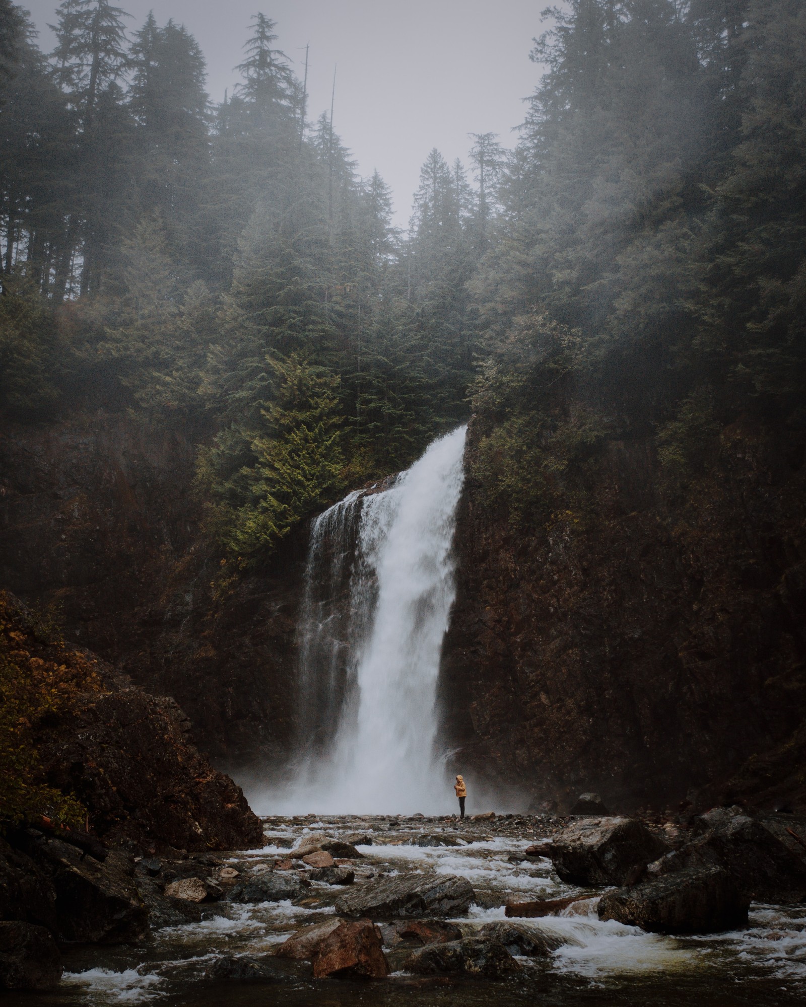 Homem árabe em pé na frente de uma cachoeira na floresta. (corpo de água, cachoeira, recursos hídricos, natureza, água)