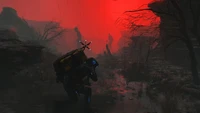 Eine einsame Figur hockt in einer gespenstischen Landschaft, umhüllt von rotem Nebel, mit schattenhaften Silhouetten, die im Hintergrund lauern - ein atmosphärischer Einblick in die Welt von "Death Stranding 2".