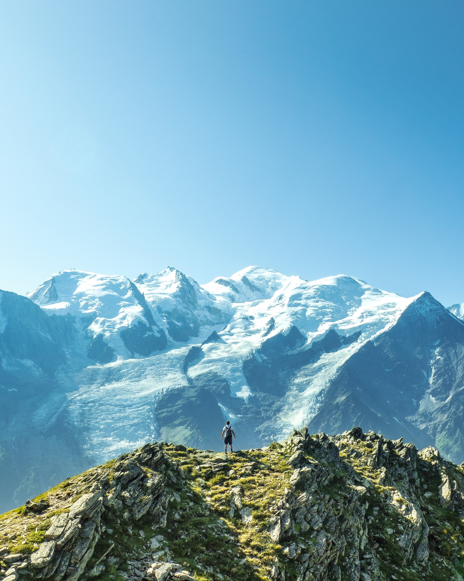 Eine person steht auf einem gipfel mit blick auf die berge (berg, mont blanc, gebirgskette, gebirgige landformen, gebirgskamm)