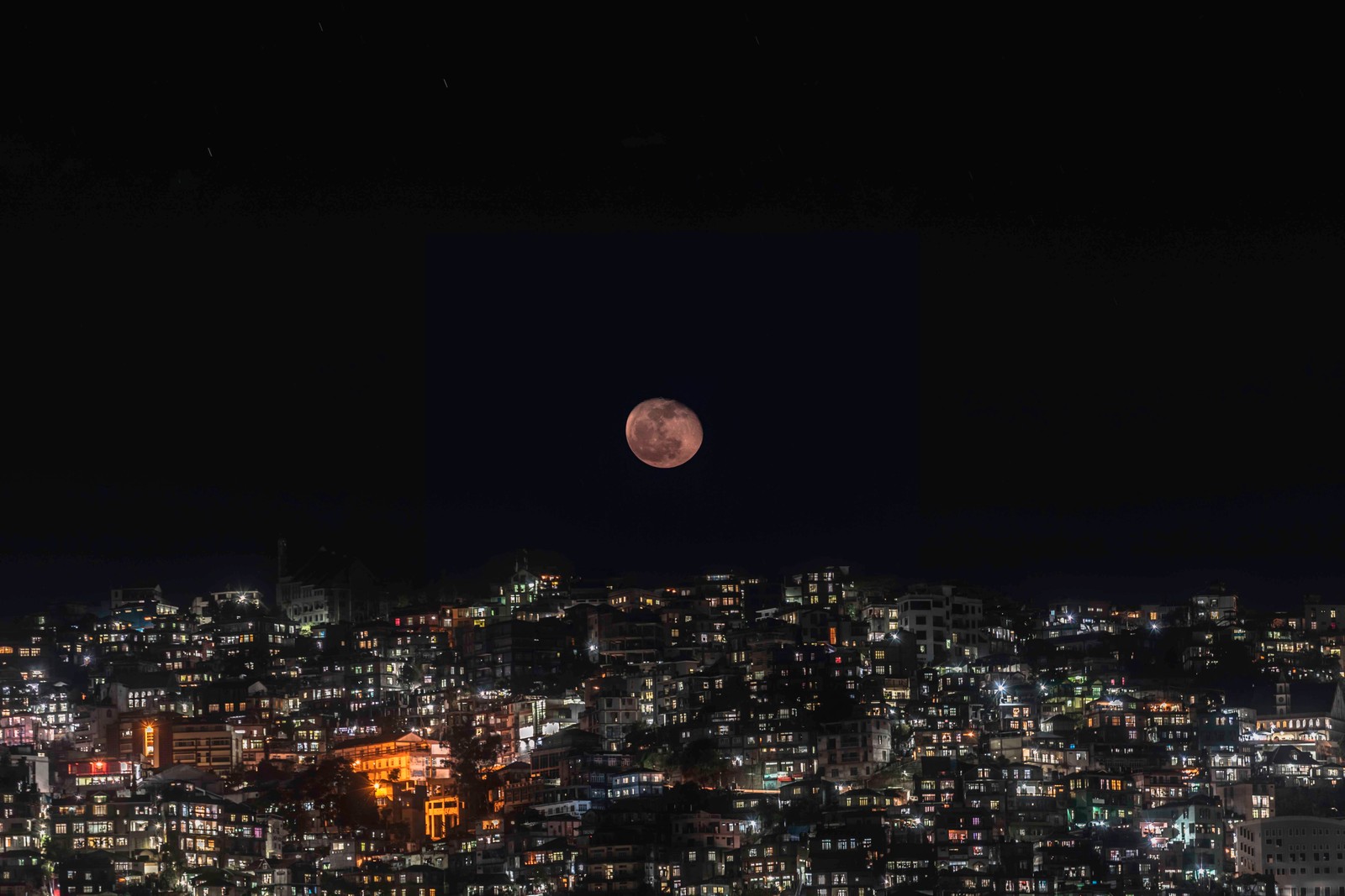 Uma vista de uma cidade à noite com uma lua cheia no céu (noite, lua, lua cheia, evento celestial, luz)