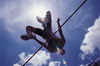 Atleta de salto alto elevándose contra un cielo iluminado por el sol