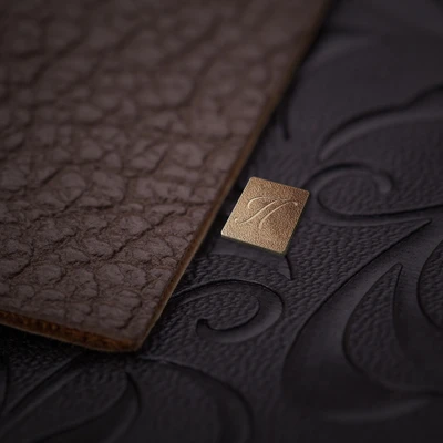 Close-up of a textured brown leather surface featuring a bronze Huawei emblem on a luxury smartphone design.