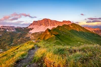 Lever de soleil sur un paysage montagneux majestueux avec des pentes verdoyantes