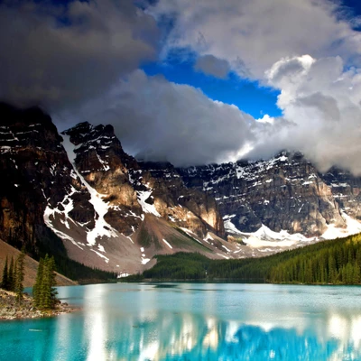 Majestätische Berge spiegeln sich in ruhigen blauen Gewässern unter einem dramatischen Himmel.