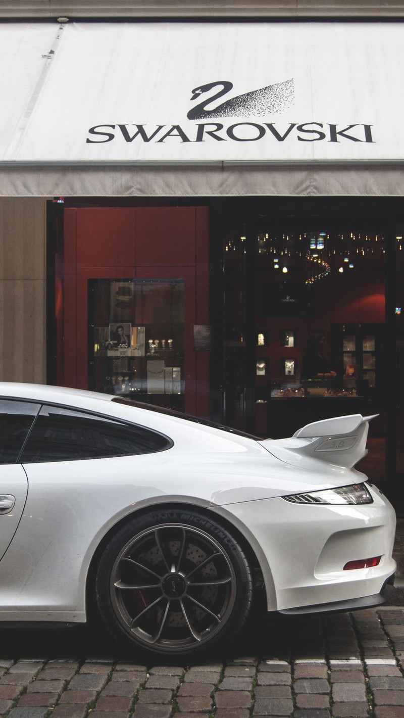 Um carro esportivo branco estacionado em frente a uma loja swarovski (fotography, porsche)