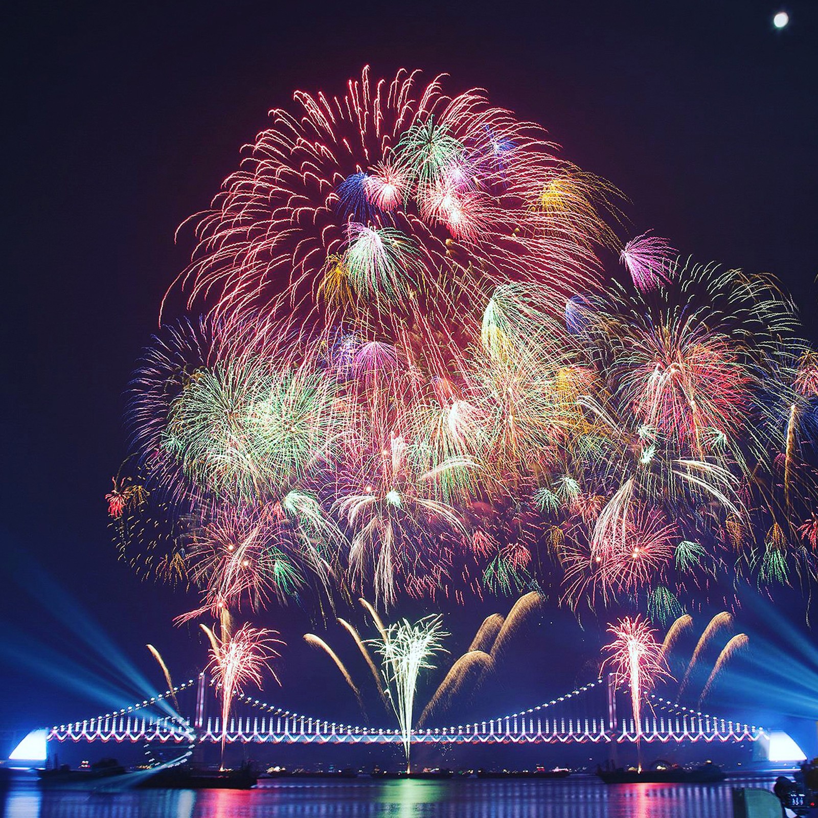 Fireworks are lit up over a bridge and a body of water (feliz navidad, merry cristmas, new year 2021)