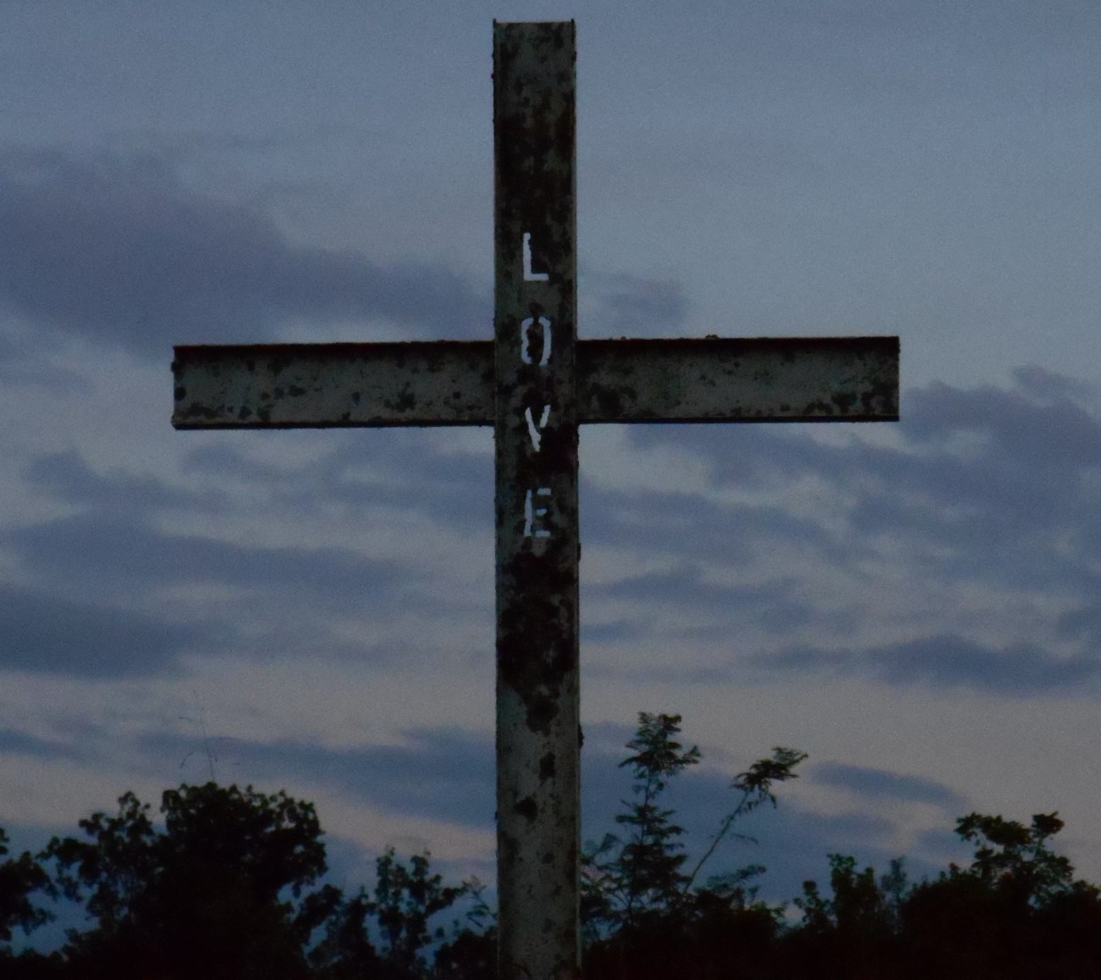 Há uma cruz com grafite no meio de um campo (cruzes, deus, jesus, amor, outro)