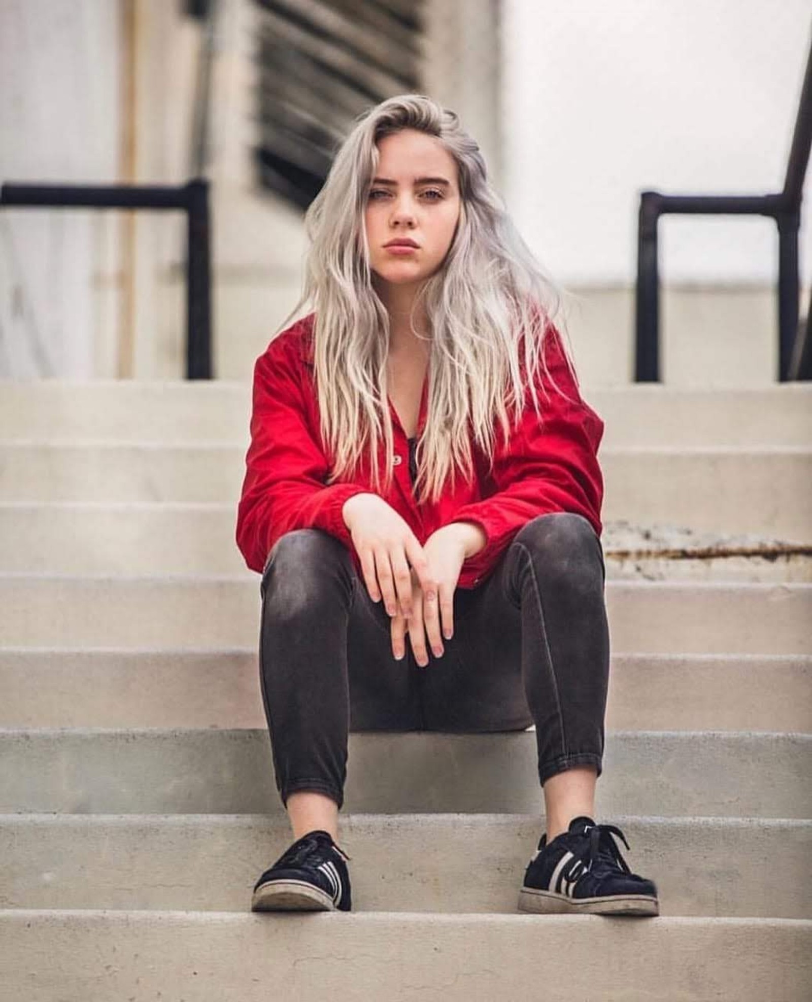 Una mujer árabe sentada en los escalones con las piernas cruzadas (billie eilish, cantora, música)