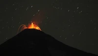 Volcan Villarrica en éruption la nuit, présentant un lac de lave et des cendres volcaniques contre un ciel étoilé