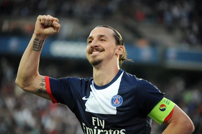 Zlatan Ibrahimović celebrates a goal with a triumphant fist pump while wearing the captain's armband for Paris Saint-Germain during a match.