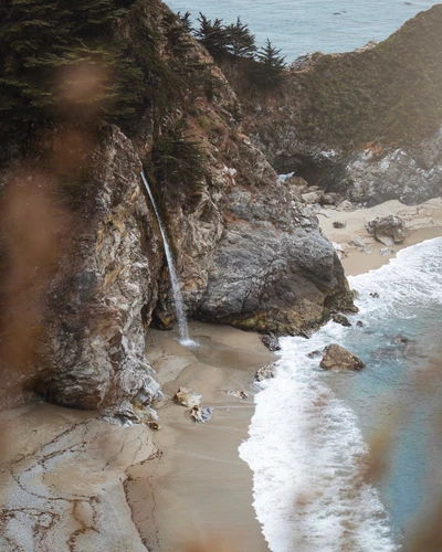 Cascata cênica na falésia que deságua em uma praia serena