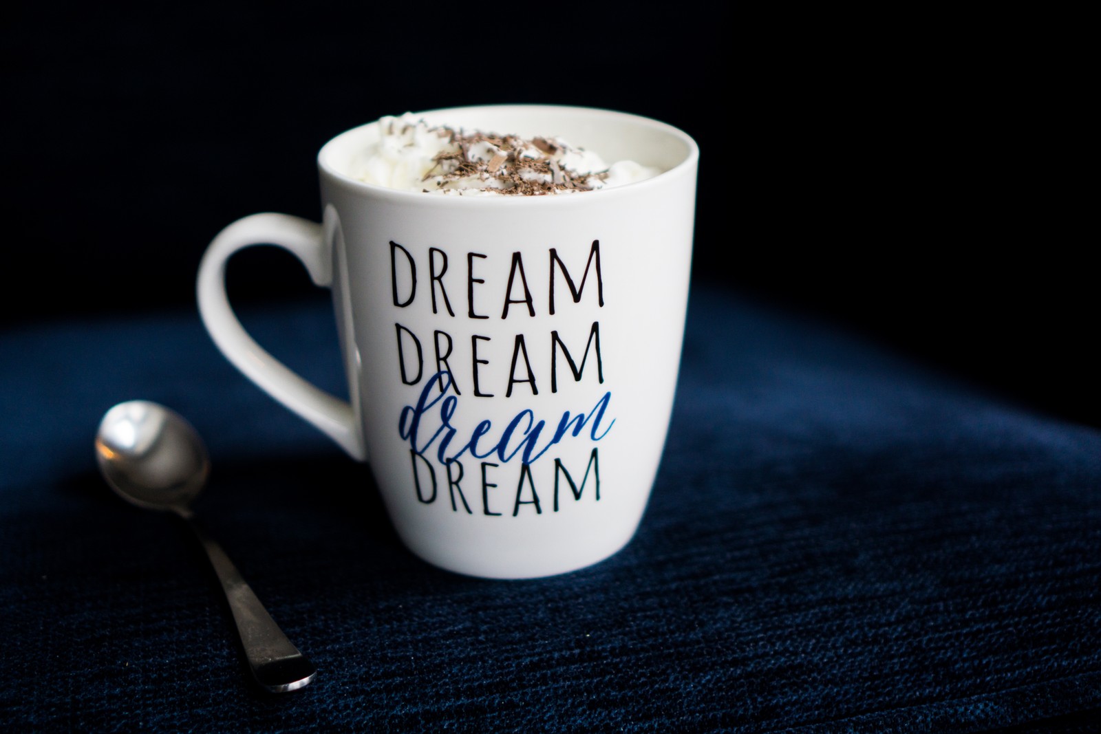 There is a cup of coffee with a spoon on a blue table (coffee, hot chocolate, cup, mug, coffee cup)