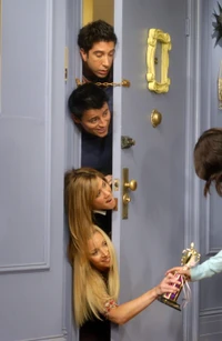 A playful scene featuring friends Ross, Joey, and Phoebe peeking through a door as Rachel hands over a trophy, capturing a lighthearted moment from a beloved television show.