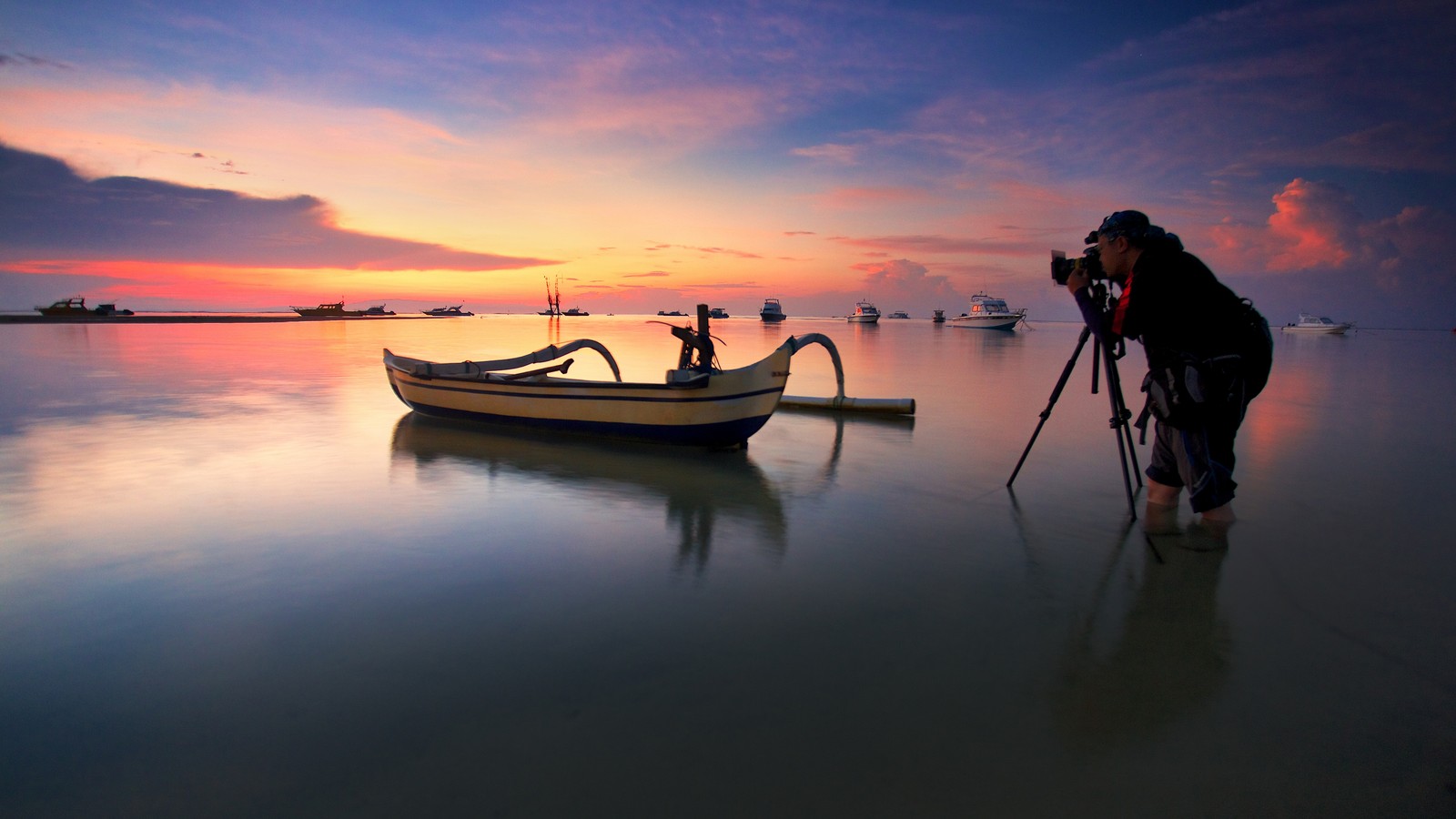 Um homem tirando uma foto de um barco na água (reflexo, nuvem, água, barco, lago)